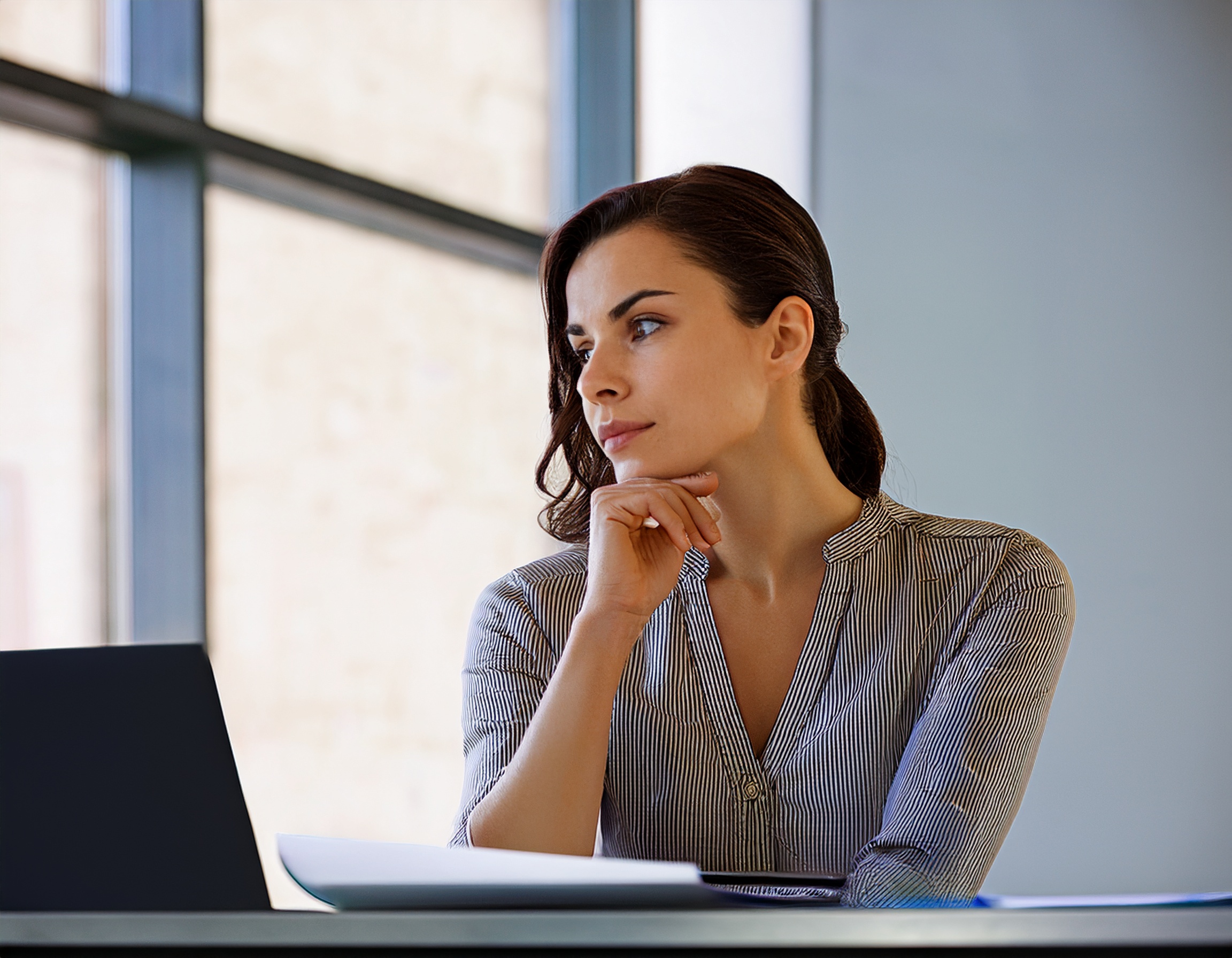 Porträt einer jungen Frau, die konzentriert am Schreibtisch arbeitet